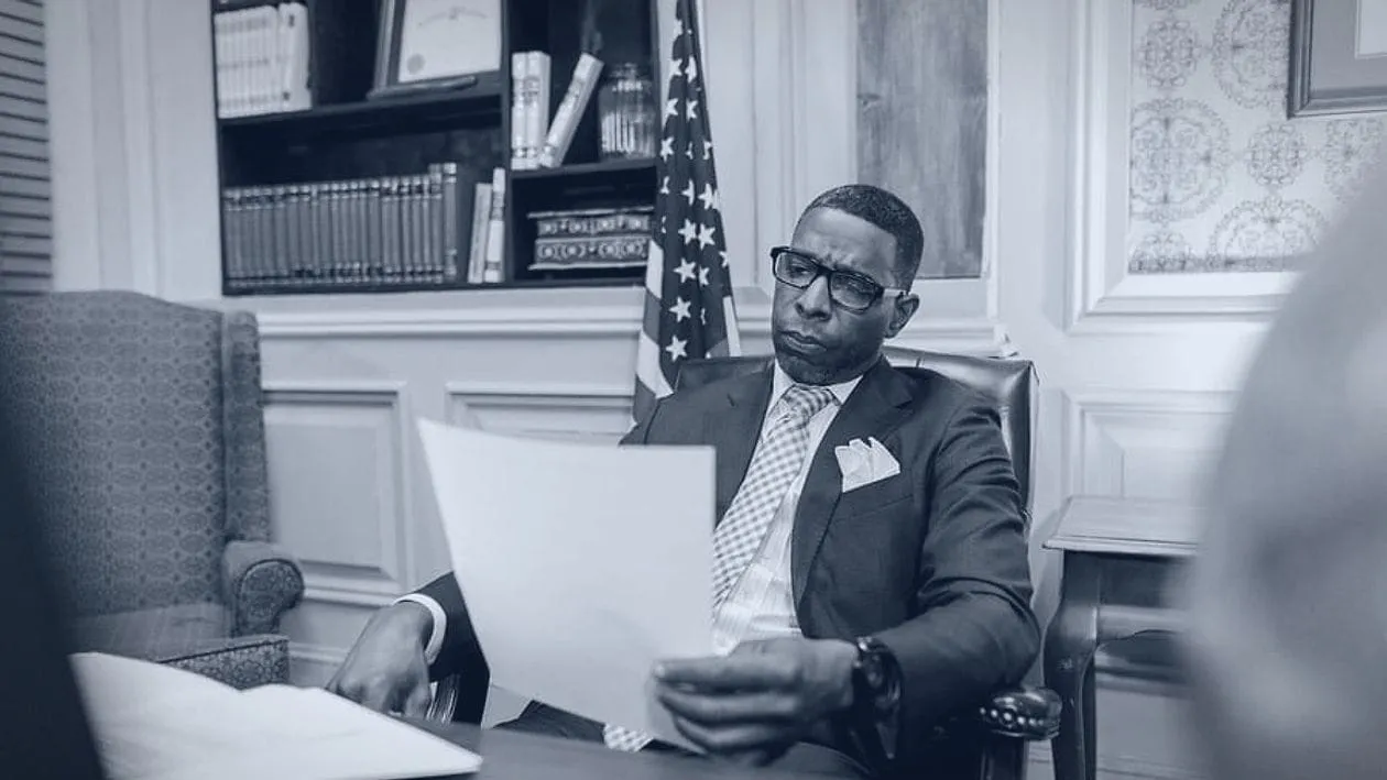A lawyer in his office reading a document, printed in navy and white.