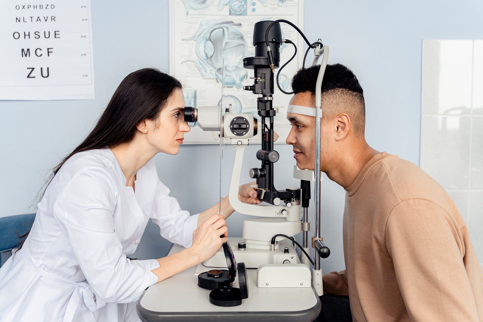 An eye specialist examining a patient’s eyes at a slit lamp.