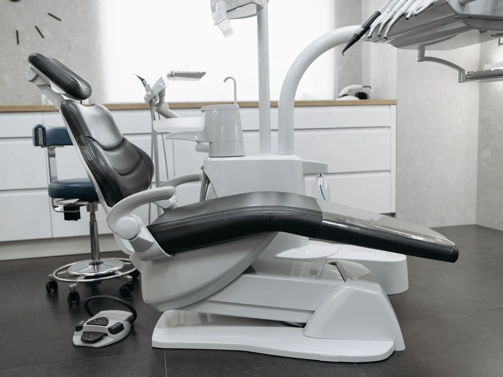 A modern dental treatment room, the chair empty under its lamp.