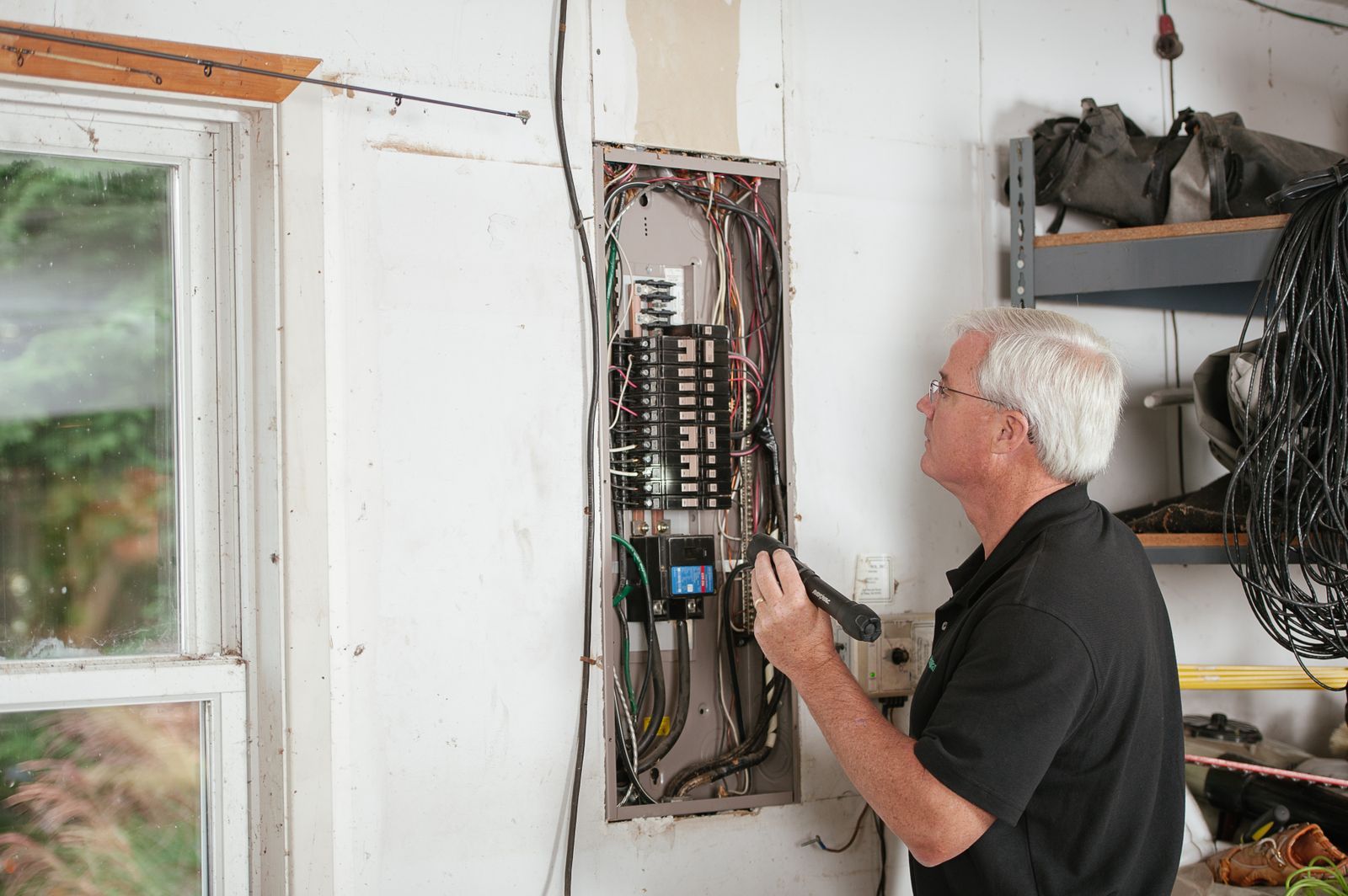 An electrician working on a fuse board in a house.