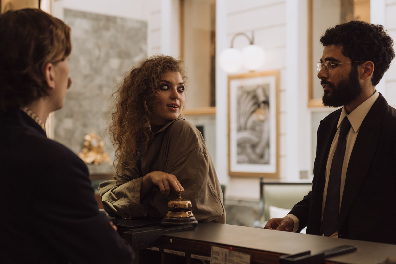 Guests chatting with the host at the front desk of a small hotel.