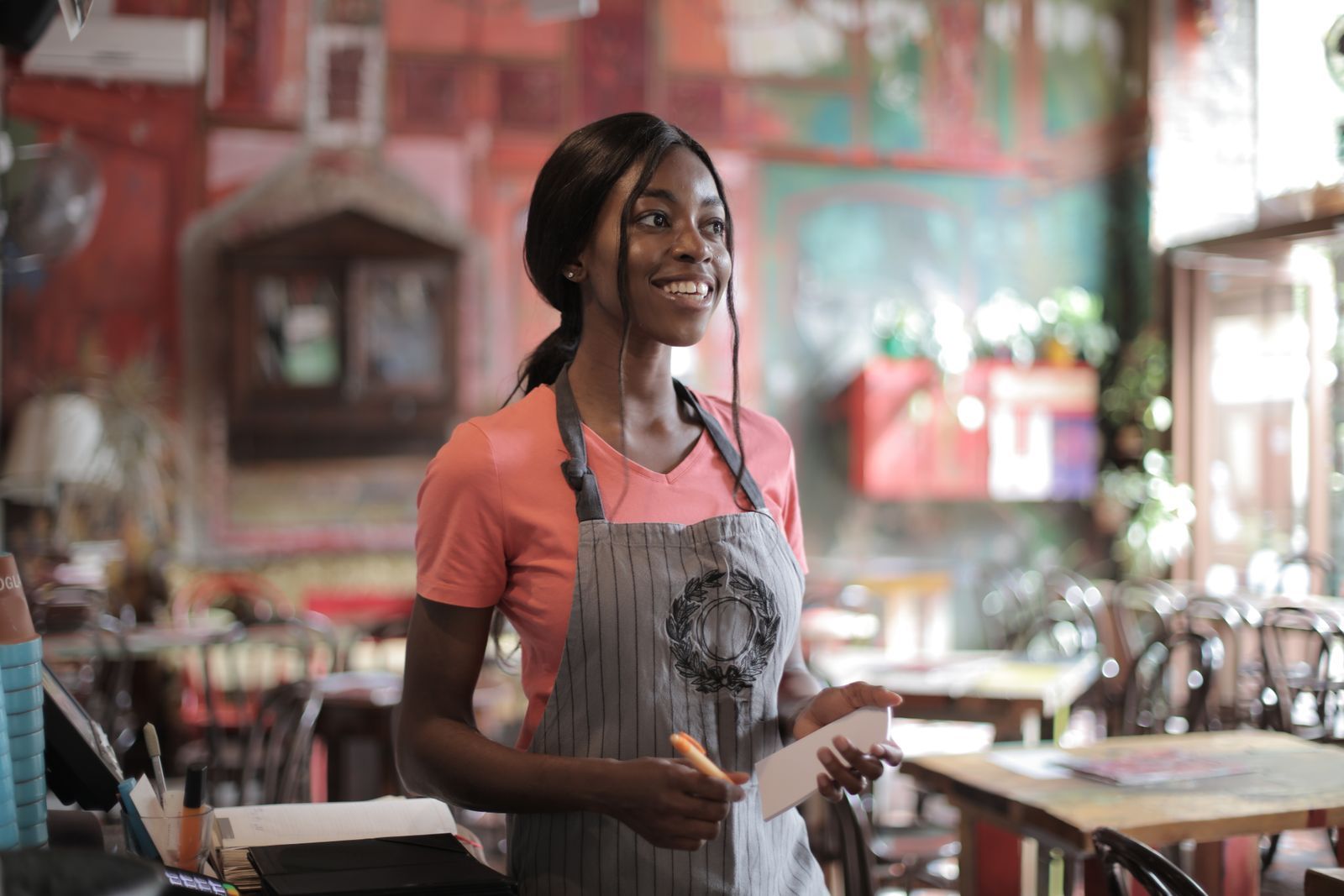 A smiling waitress with her notepad, ready to take an order in a busy family restaurant.