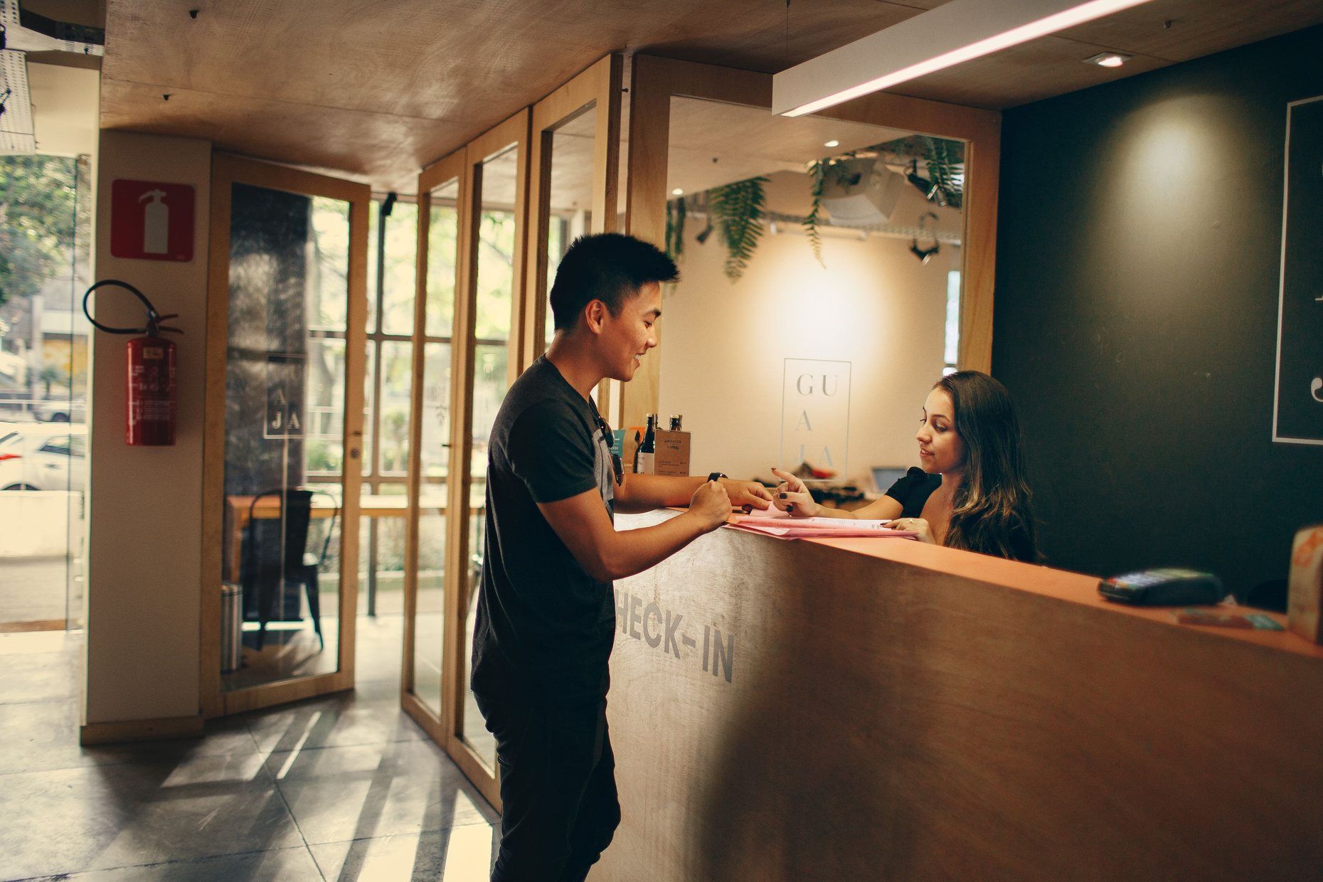 A guest checking in at a modern hotel front desk while the receptionist looks up his booking.
