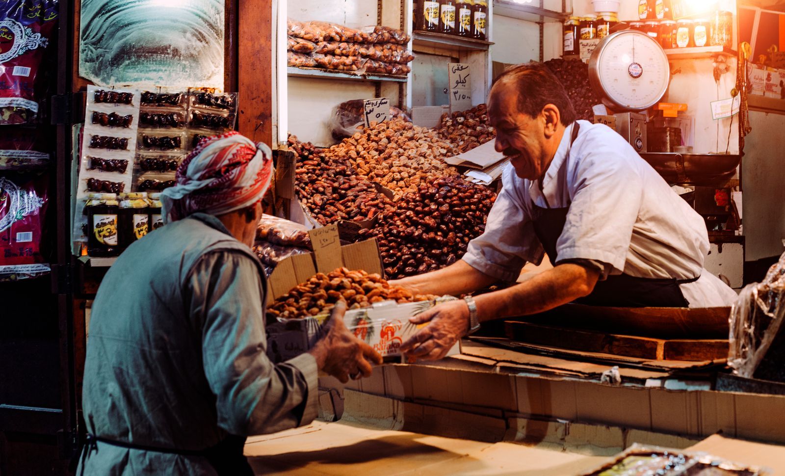 A trader weighing out dates for a customer at a spice and dates stall.
