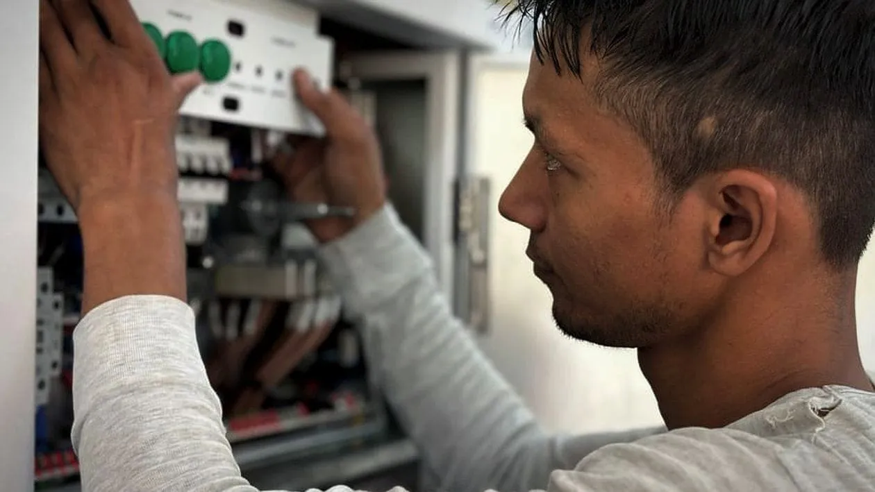 An electrician working on a fuse board, concentrating on the wiring.