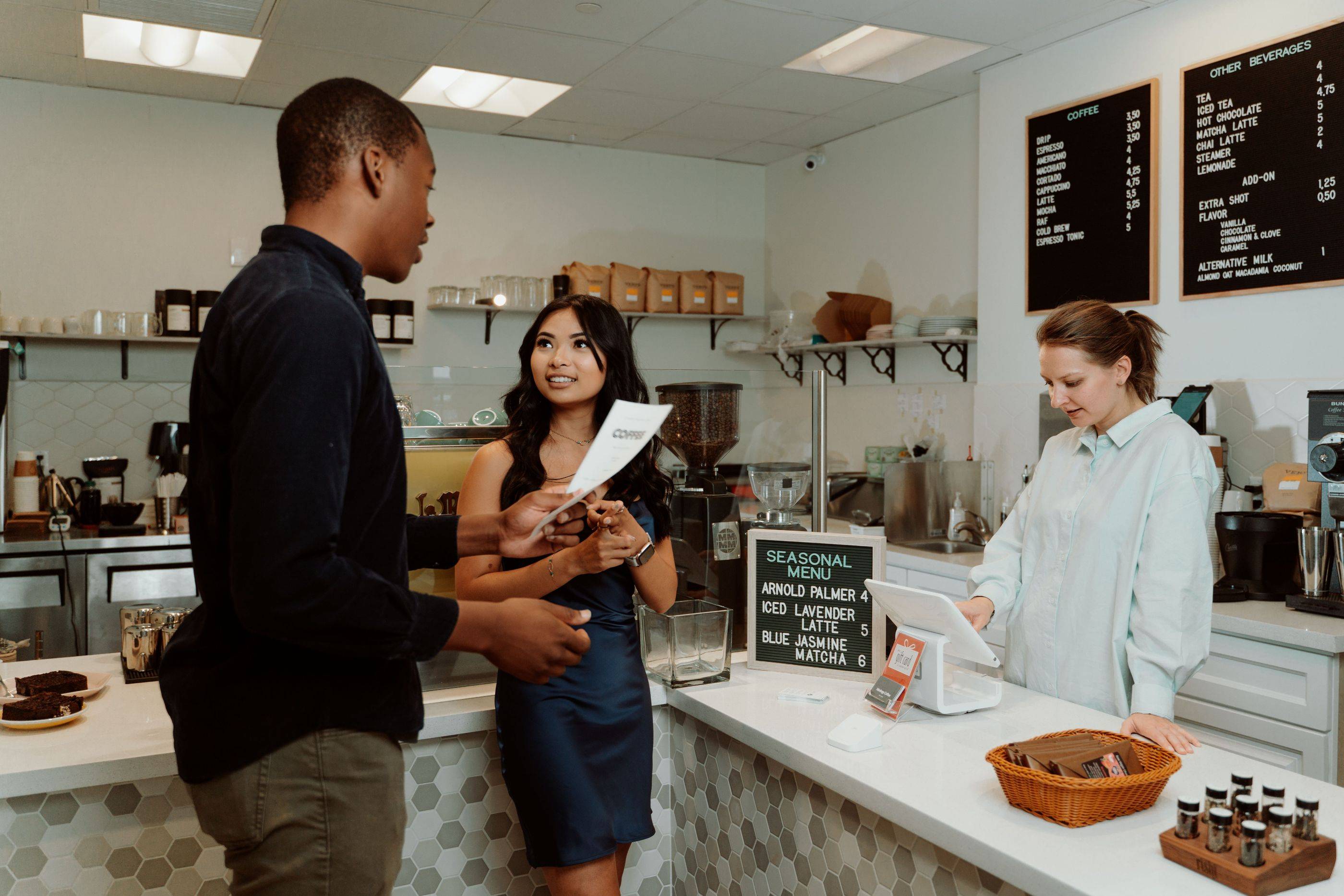 Customers decide on their order at a café counter while the barista gets ready to serve