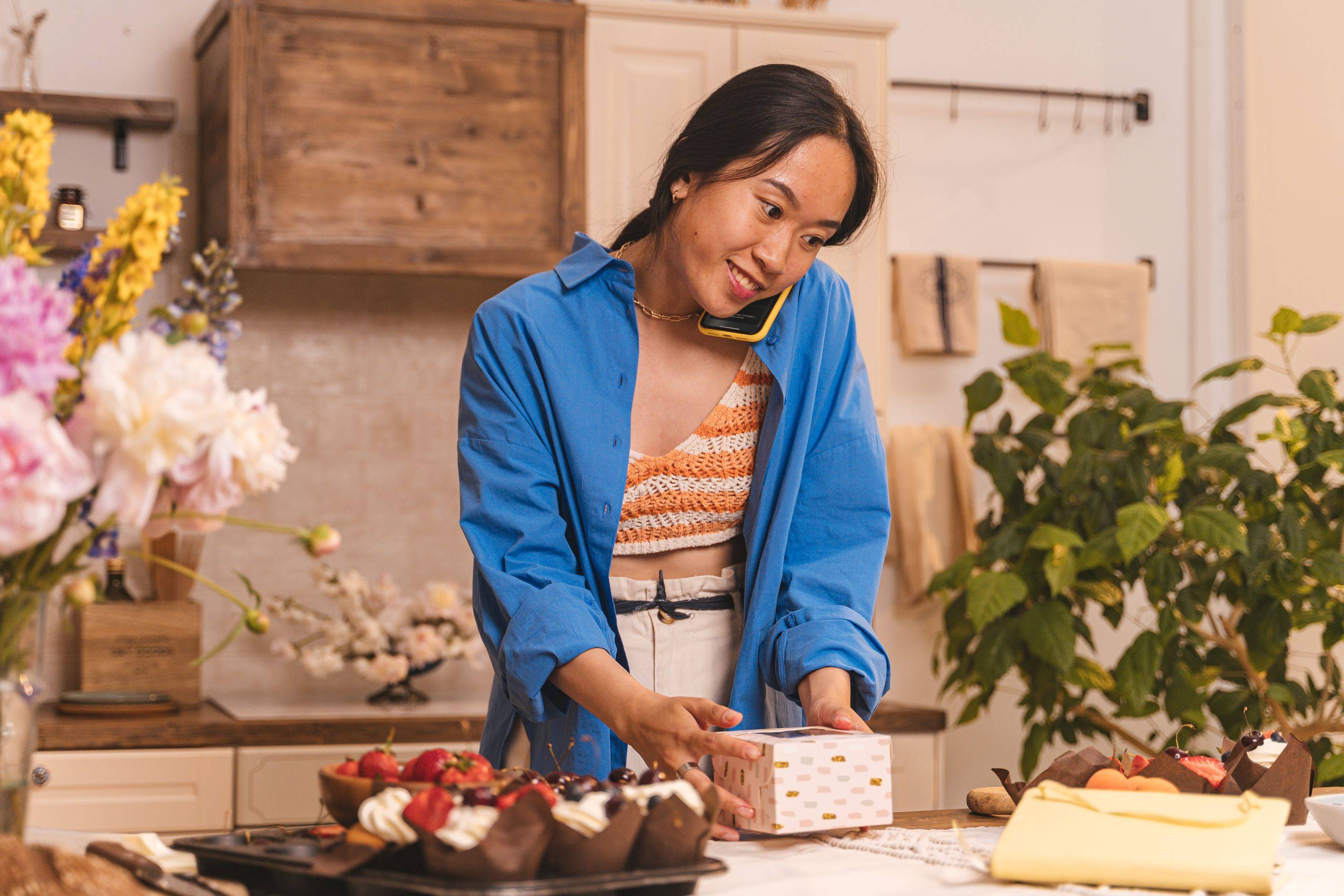 A bakery owner takes a phone order while boxing up cakes