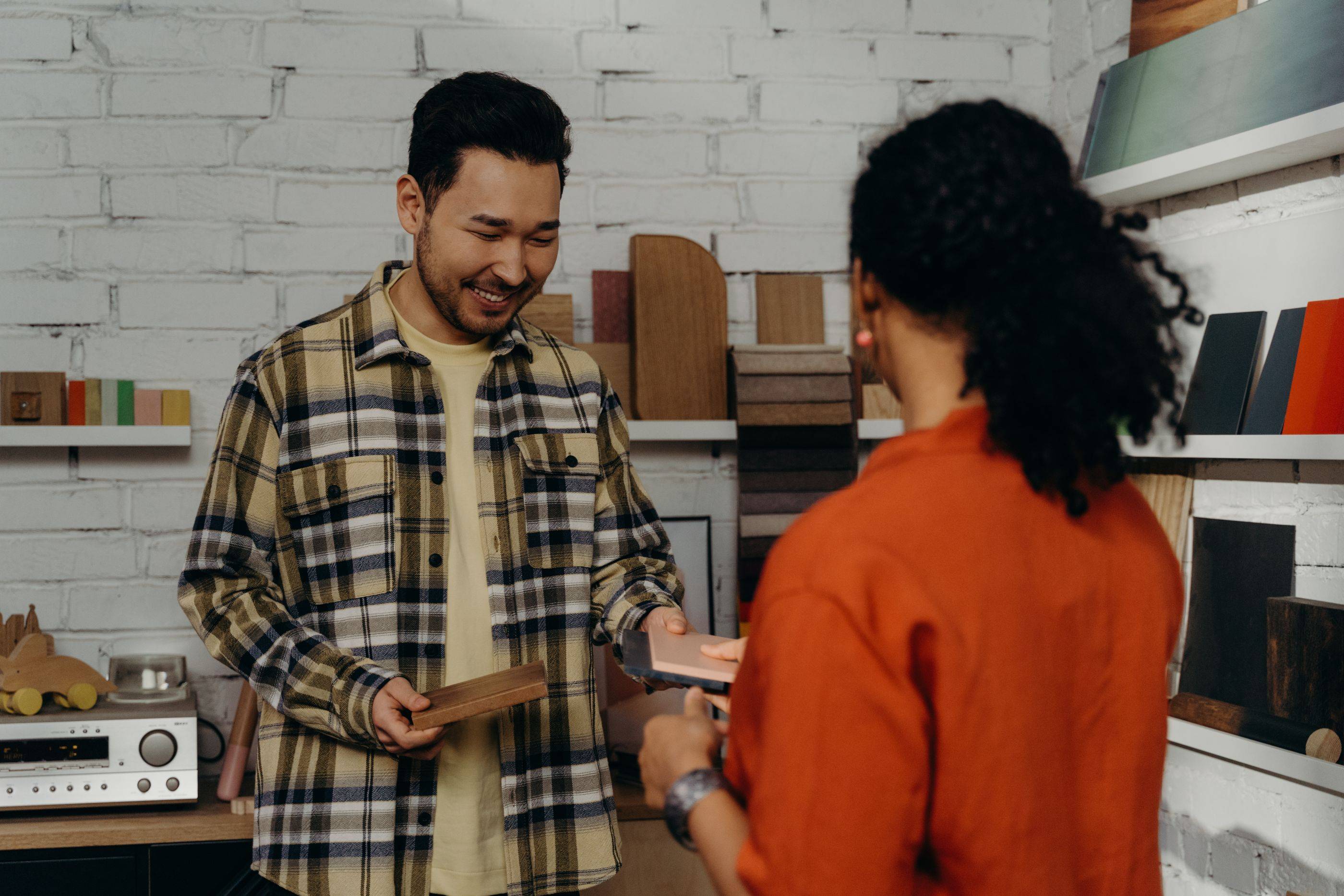 A shop owner smiles as he talks a customer through her order
