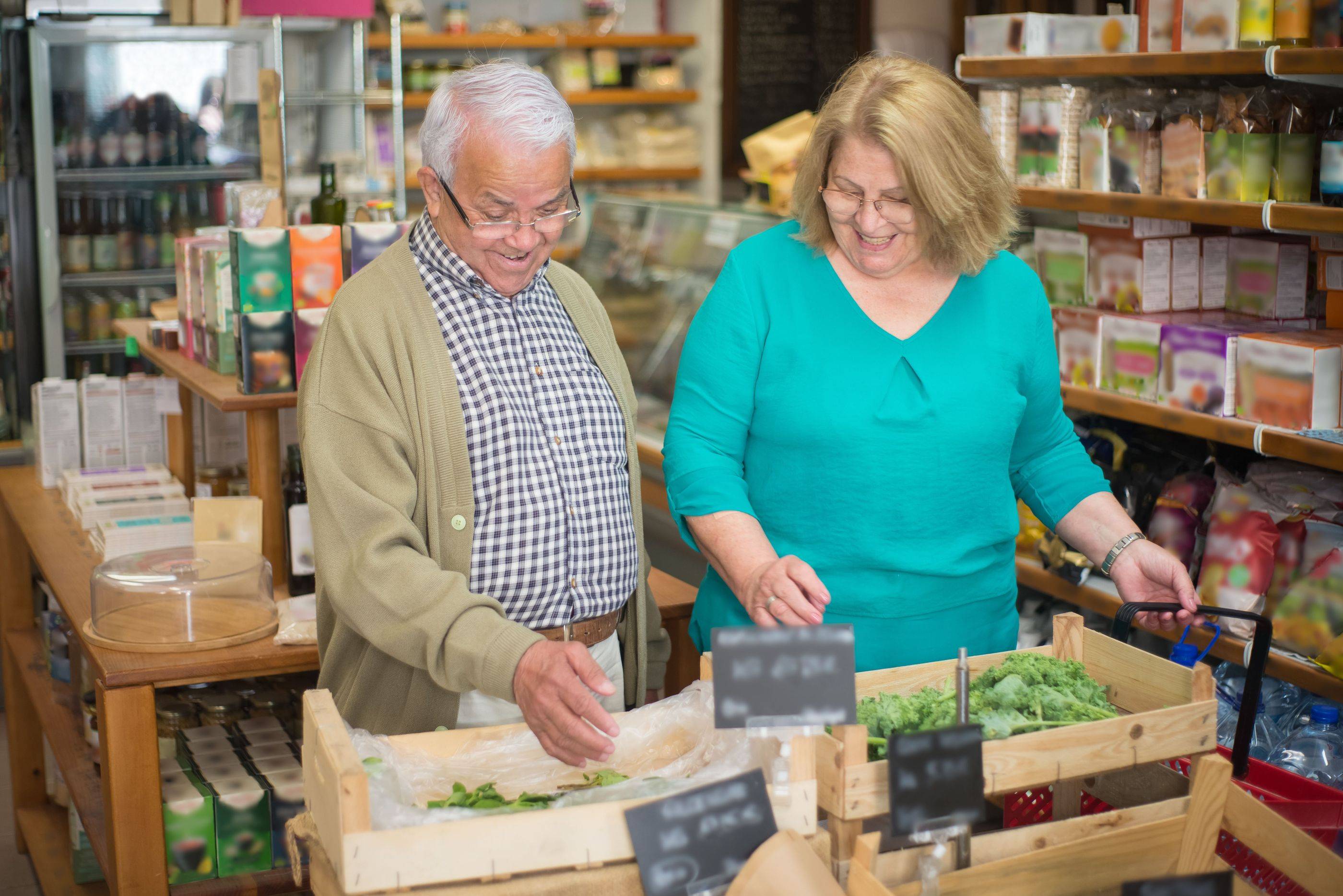 Two regulars pick fresh greens from the crates in a well-stocked corner deli
