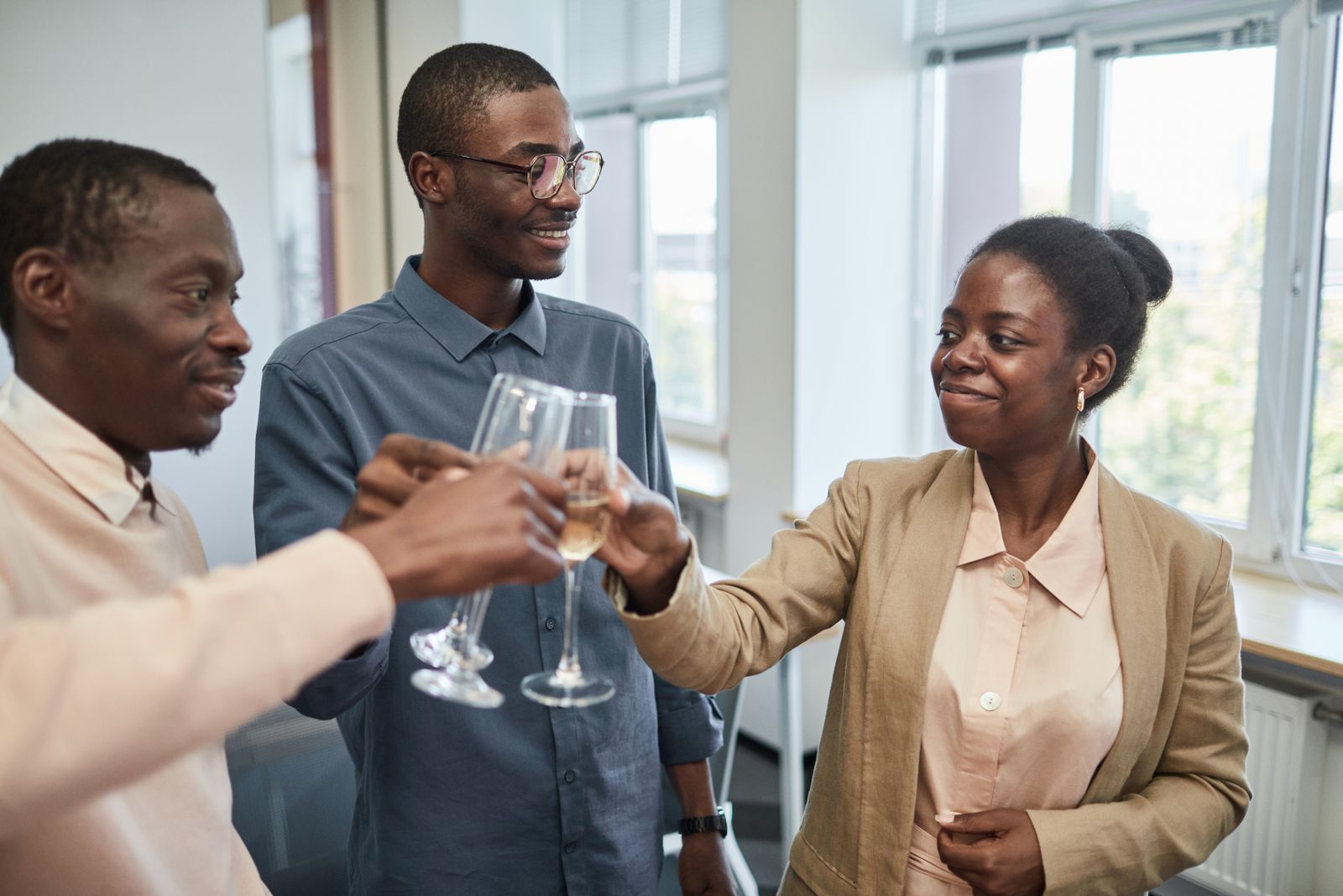 Three colleagues raising their glasses together, smiling, at the end of a good day.