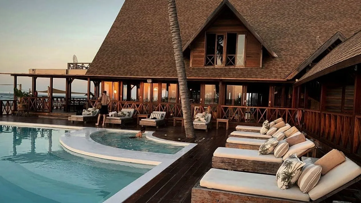 A wooden resort hotel with a pool at dusk.