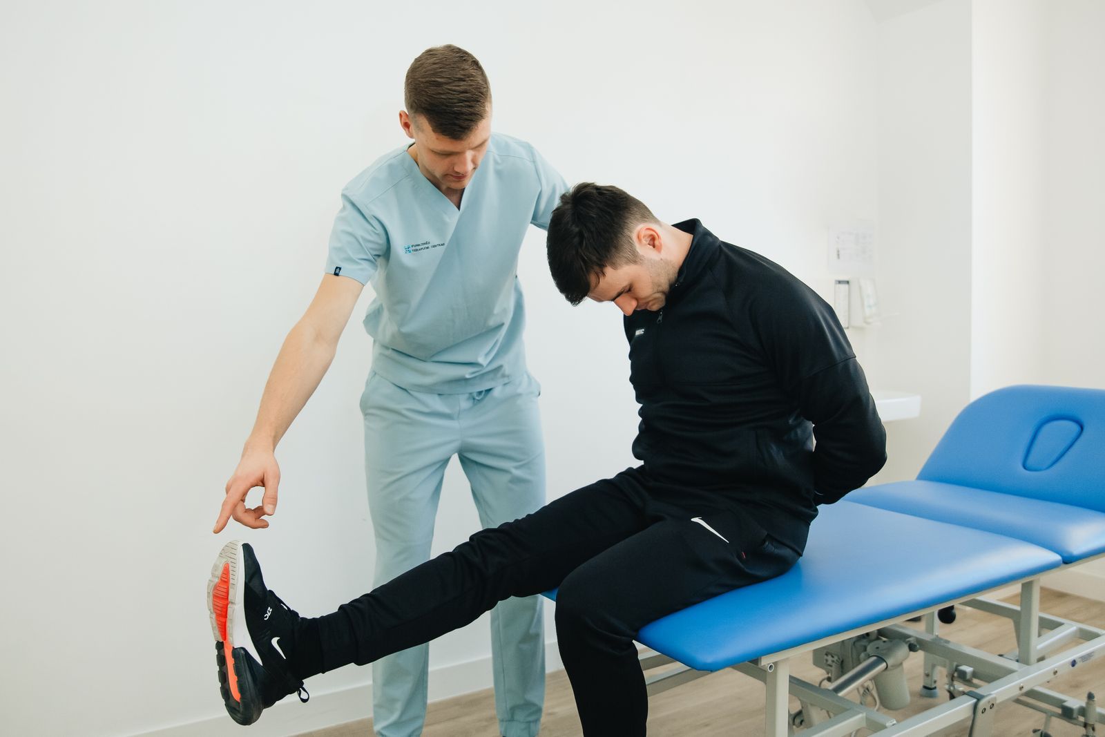 A physiotherapist guiding a patient through a stretch on the treatment table.