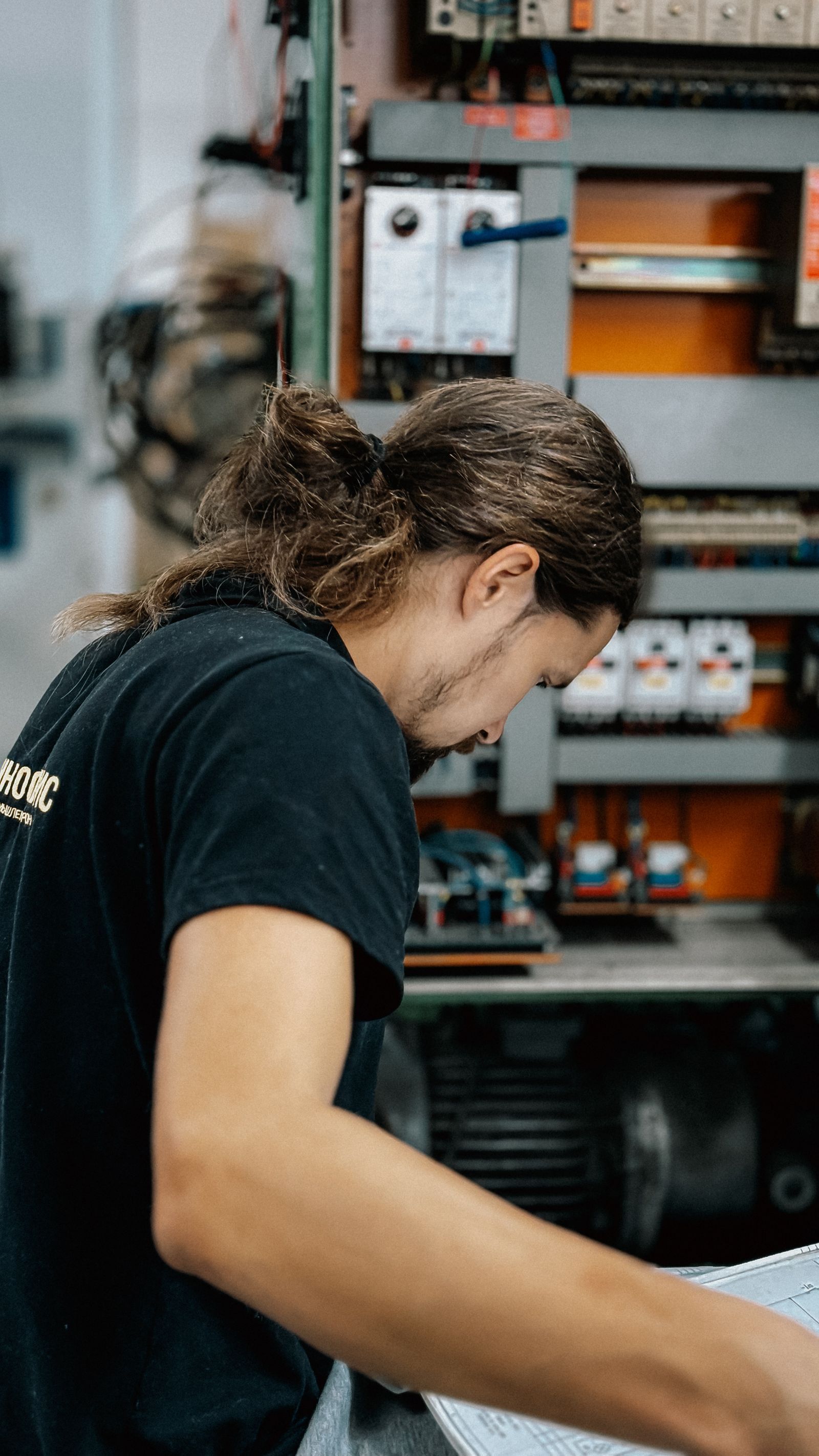 An electrician checking the connections inside an open electrical panel.