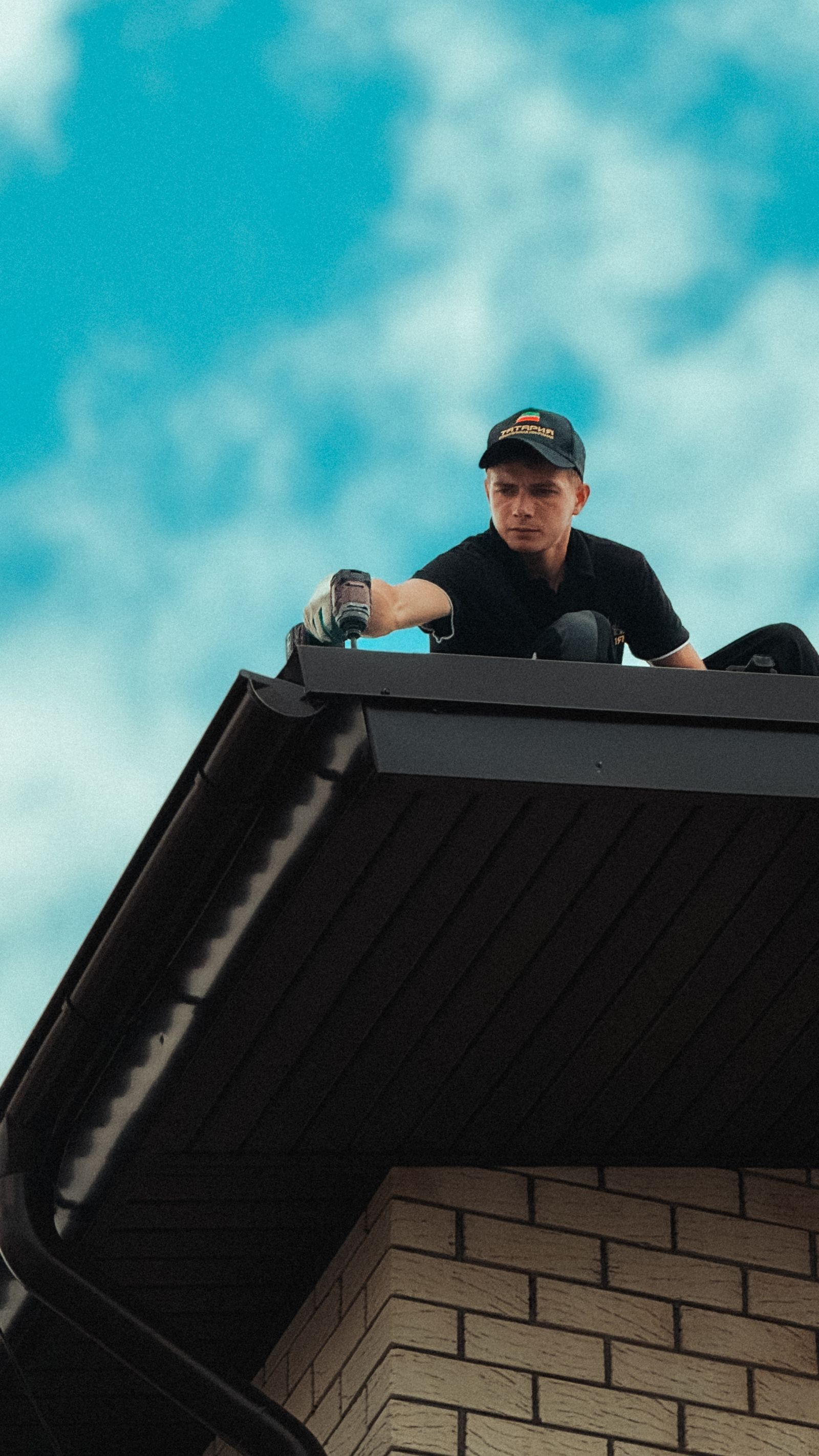 A roofer at work on a house roof on a sunny day.