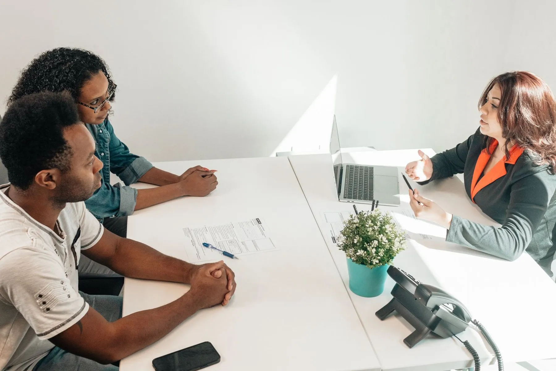 A lawyer at a bright office desk going over papers with a couple.