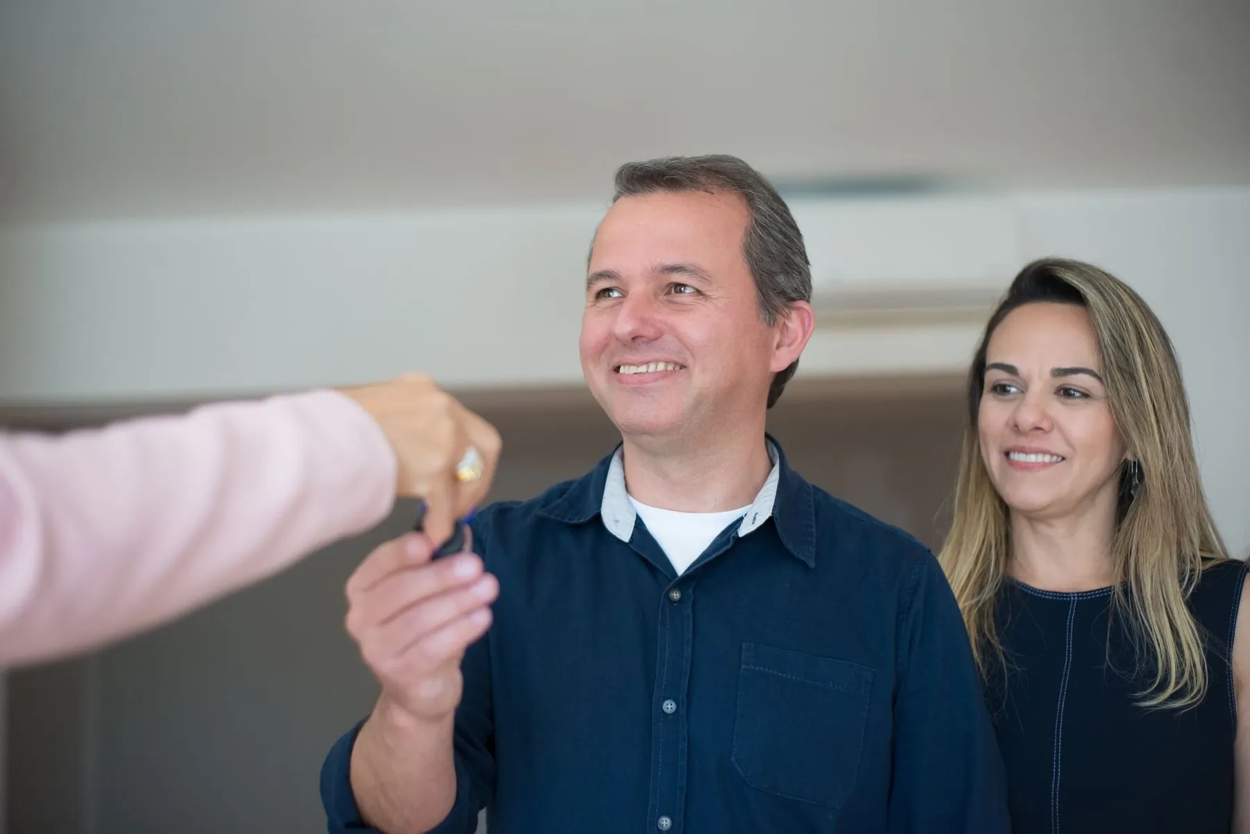A smiling couple being handed the keys to their new home.