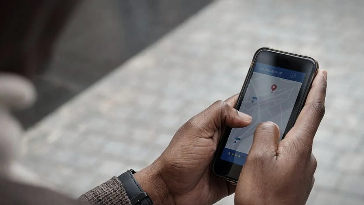 Hands holding a phone showing a map with a location pin.