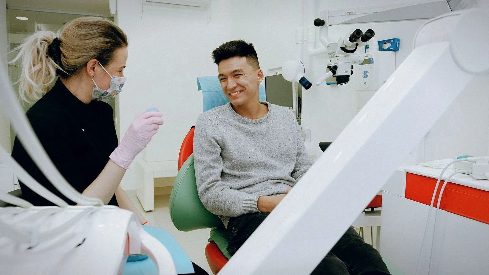 A dentist chatting with a smiling patient in the chair.