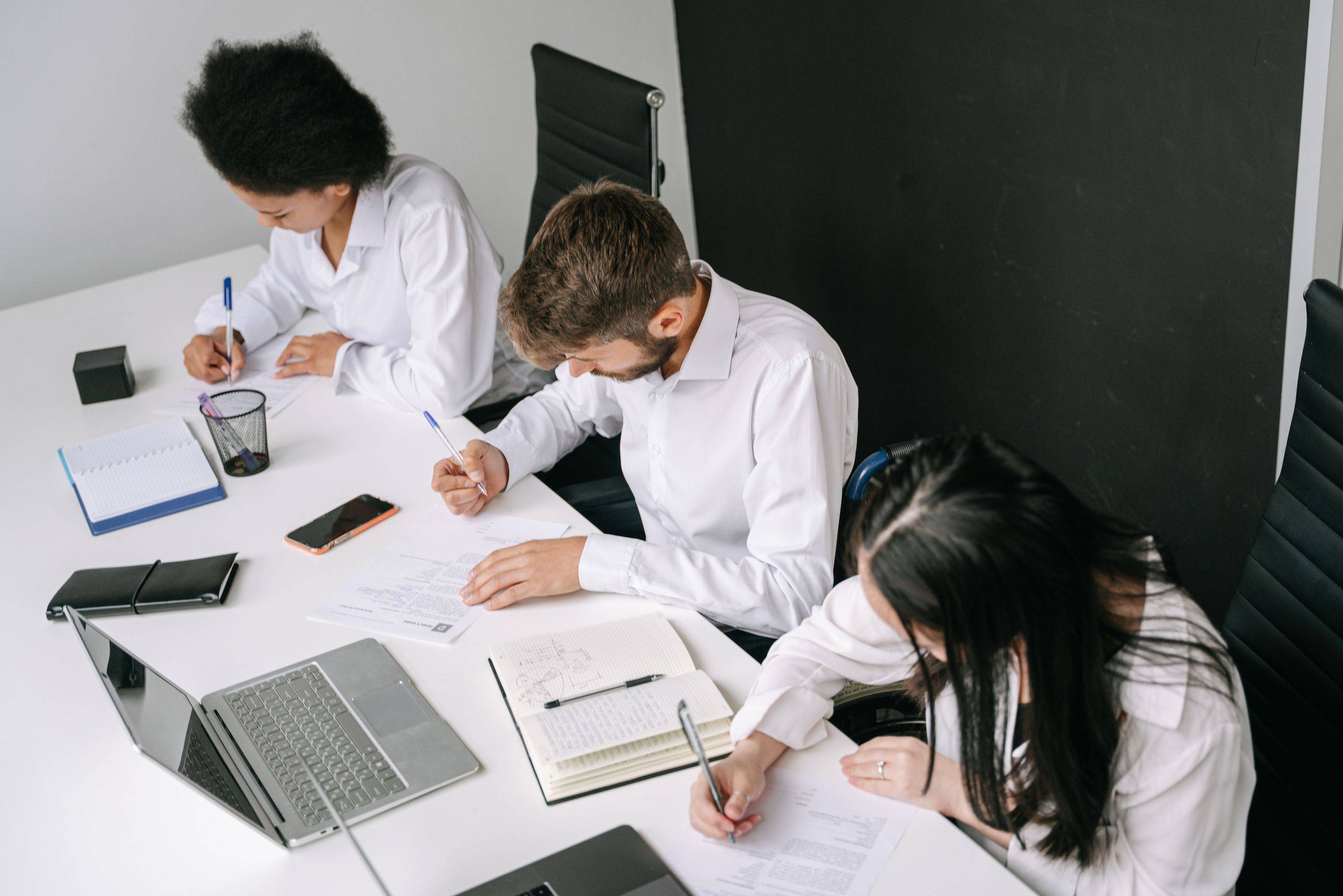 Seen from above, three specialists write up their notes on a case at a shared desk
