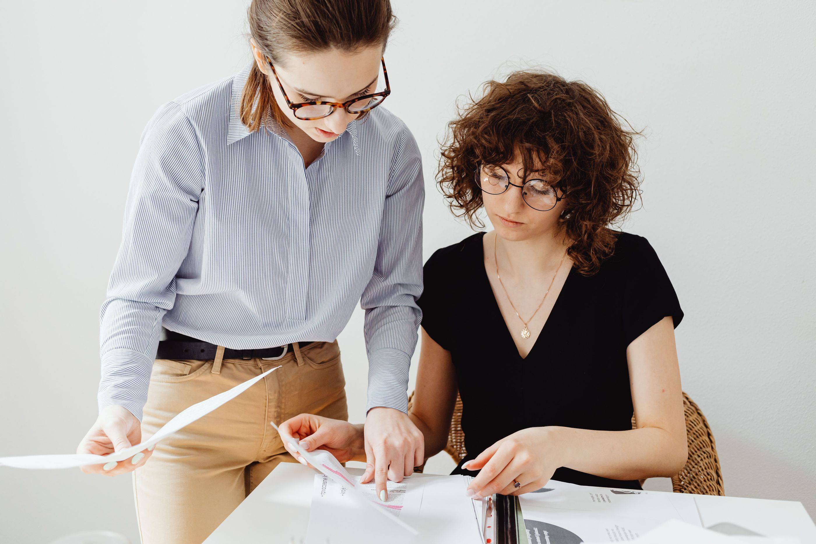 Two specialists check the week’s printed reports together, one leaning over the table