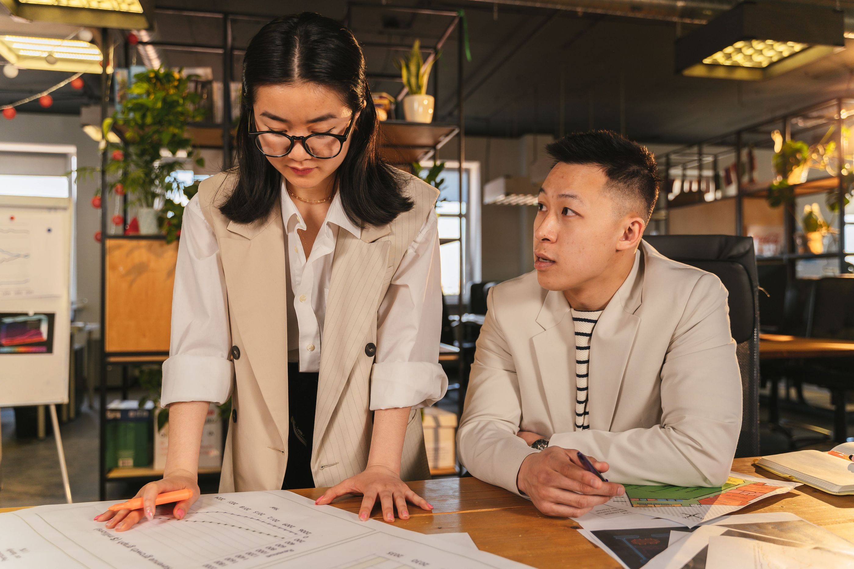 Two specialists go through a client’s case on a large printout spread across their desk