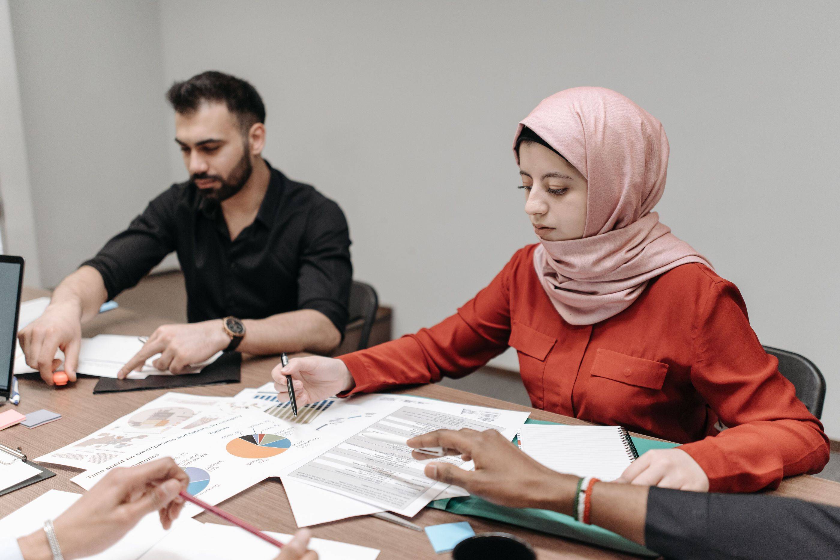 A small team works through printed charts and notes around a meeting table