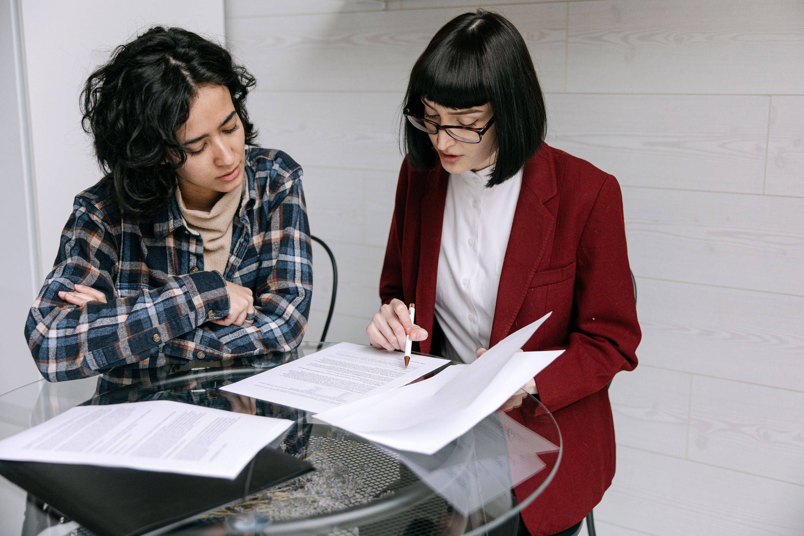 Two specialists read through a case file together, one marking a page with her pen